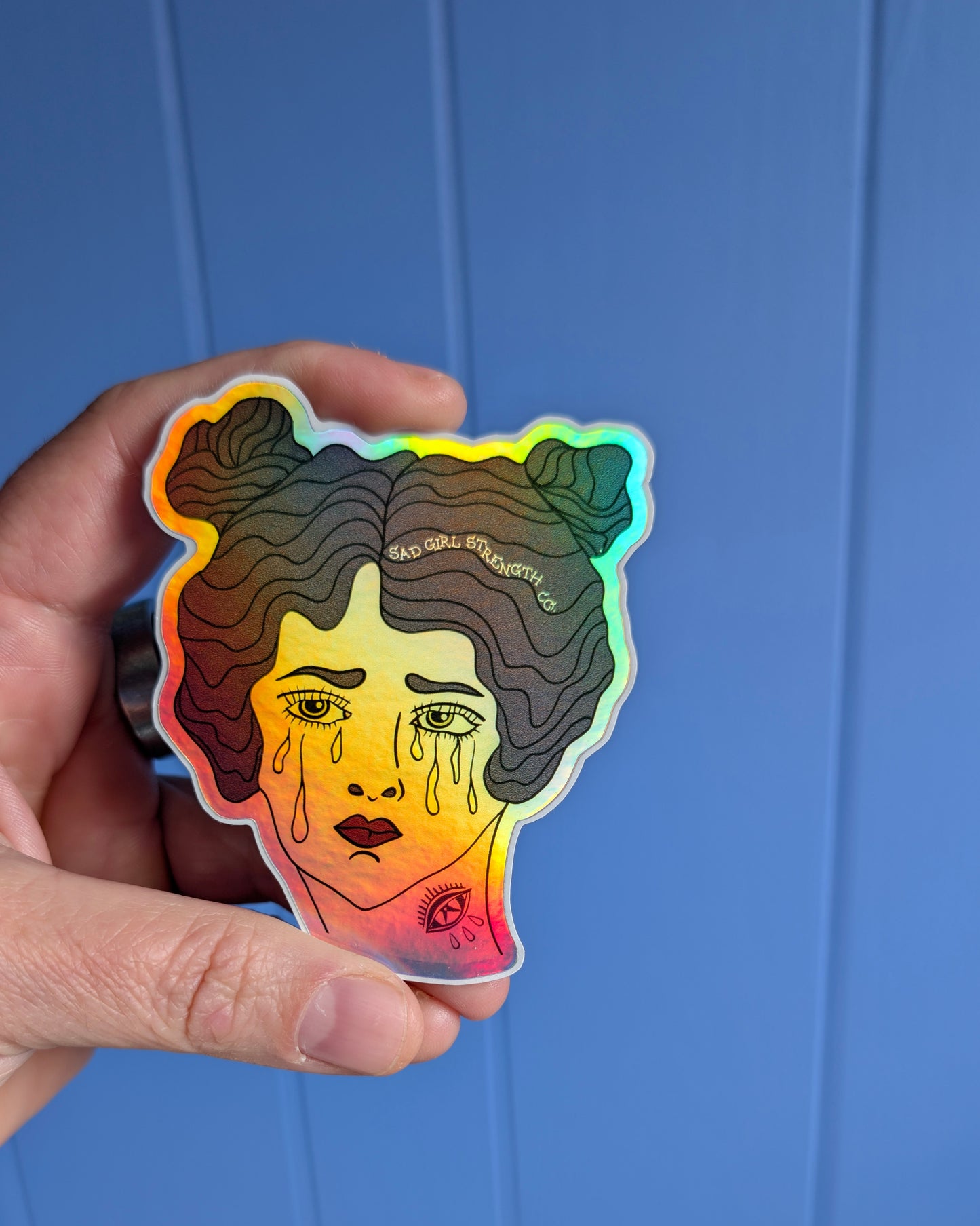 Holographic sticker of a woman's face held against a blue background